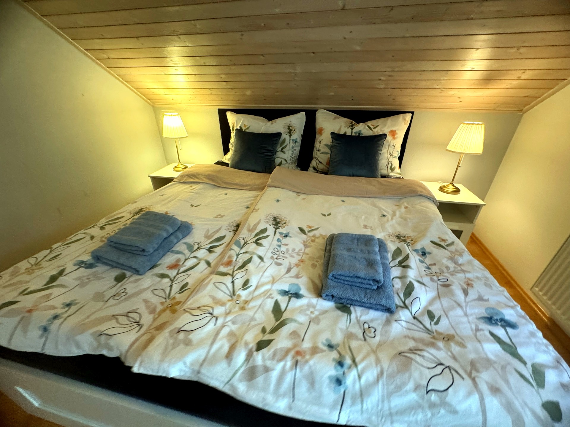 Ložnice ustlaná jako v hotelu — povlečení, ručníky, lampičky